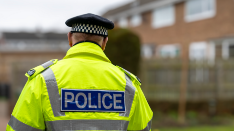 The back of a police officer wearing a high vis jacket.