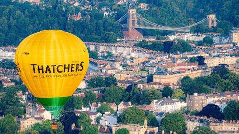 A picture of a hot-air balloon in the foreground and the bridge in the background, taken from the air