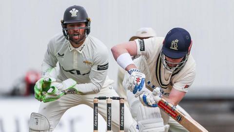 Left-handed Dan Mousley watchfully turns a ball to the legside as Surrey wicketkeeper Ben Foakes watches behind the stumps