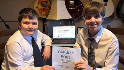 Llun o Caio a Celyn yn gafael mewn copi o Papur y Bobl