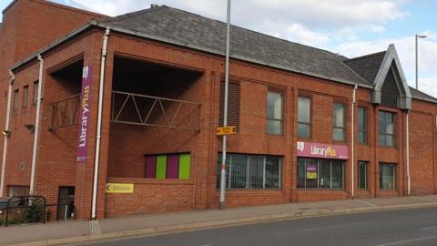 A red brick building with a library sign above the entrance. 