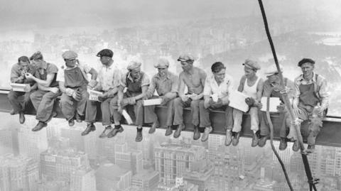 Steel workers atop the 70 story RCA building in Rockefeller Center eating lunch on a steel beam