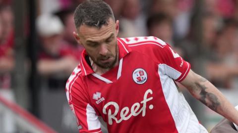 Scott Malone looks down towards the ball while playing for Crawley Town
