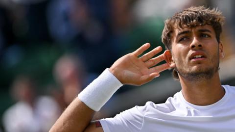 Flavio Cobolli cups his ear towards the crowd during win against Marin Cilic in Wimbledon round four 