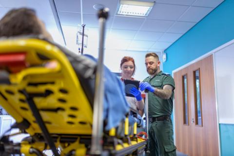 A paramedic handing over a patient to a medic