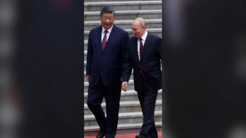 Chinese President Xi Jinping and Russian President Vladimir Putin in conversation at the bottom of some steps.