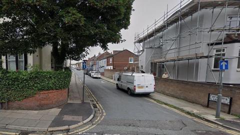 St Mary's Grove, Walton Village, showing a tree on the left in a front garden on the left corner house and scaffolding on a building having refurbishment work done on the right hand corner house