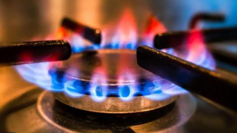 A close up shot of a lit gas hob plate with blue and orange flames