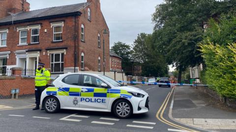A police officer and a vehicle in front of a cordon on a Nottingham street