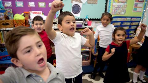 Primary school children cheering in classroom