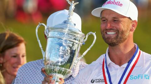 Wyndham Clark smiling while holding the US Open trophy