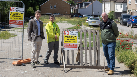 Residents stand beside anti-fly-tipping signs at the cleared Albert Road site near Sutton Station.