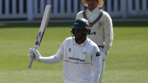 Rishi Patel holds up his bat to acknowledge his 150