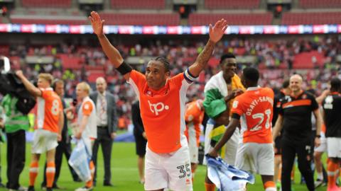 Neil Danns, while playing for Blackpool, celebrates to the fans with his arms out wide after his side's victory against Exeter City in the League Two play-off final at Wembley back in 2017. 