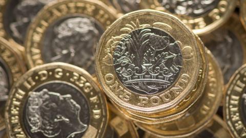 A pile of one pound coins with both tails and heads facing up.