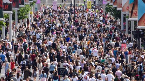 A large crowd of people walk outside Wembley Stadium.