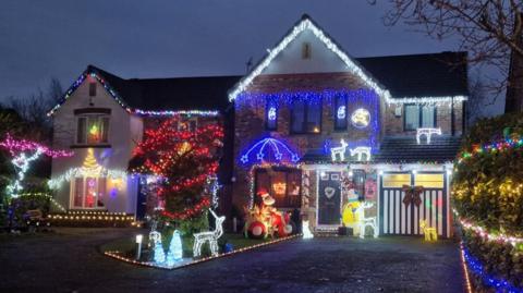 Two detached houses covered in Christmas lights.