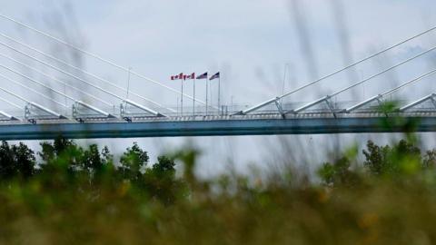 US and Canadian flags seen flying side by side on a bridge