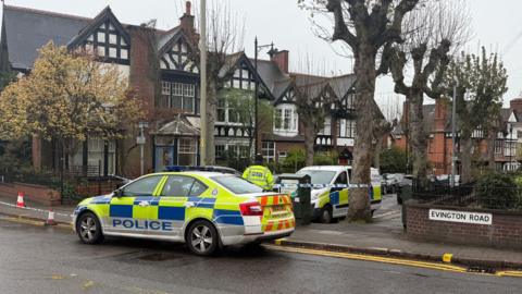 St James Road. A police cordon is in place across the road, with a police car blocking the entrance.