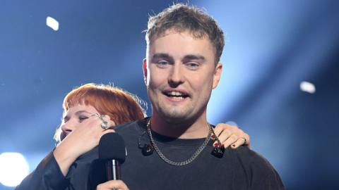 Sam Fender is hugged by a bandmate as he wins the Mercury Prize