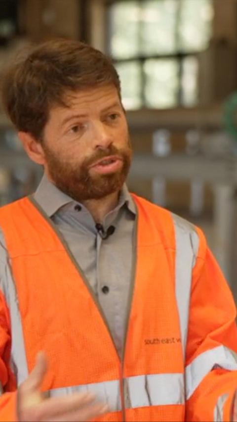 Man with ginger hair and beard wearing hi vis jacket indoors