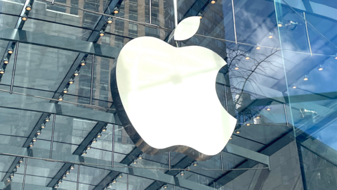 The apple logo, a large silver apple with a bite taken out of it, on the side of a building