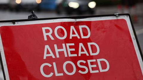 A street sign that says 'road closed' in white capitals on a red background