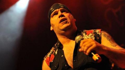 Blaze Bayley of Wolfsbane performs on stage in this archive image. He is wearing a mainly black top and holding a microphone.
