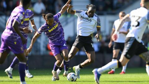 Lamine Cisse, in a purple Stoke City away kit, competes for the ball with David Ozoh, wearing a white Derby County home kit, during their match
