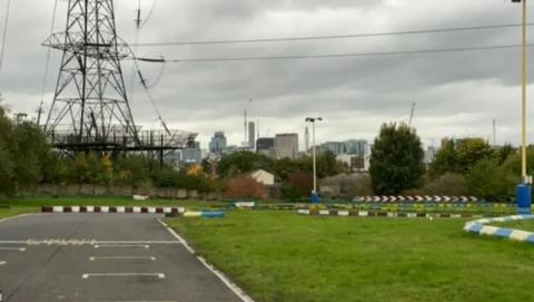 A grassy area with pylons in the background and a go cart circuit running around the grass