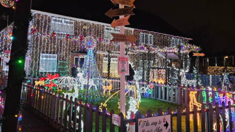 A snowy scene of a house covered in illuminations