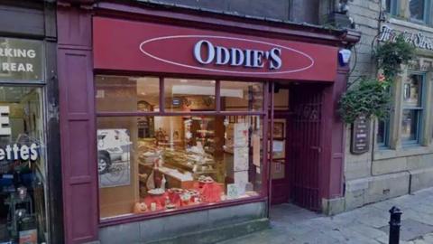 Street view of the red shop front of an Oddie's bakery in Colne