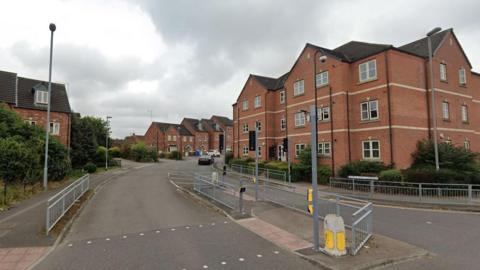 Streetview image of a modern housing estate with individual houses and a block of apartments