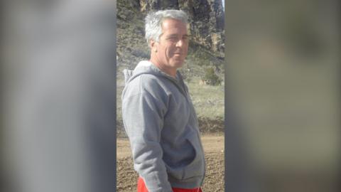 Jeffery Epstein has grey hair and is wearing a grey hoodie.