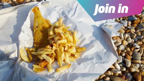 Fish and chips on white paper on a pebble beach