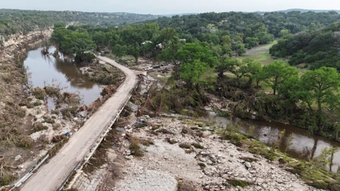 A picture taken from above shows damage to river banks and a bridge from the flooding in Texas