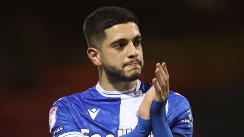 Ruel Sotiriou clapping his hands while walking on the pitch at the end of a match for Bristol Rovers