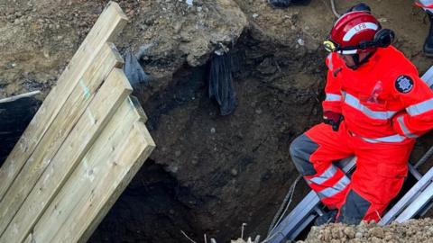 Firefighters rescuing someone from a hole