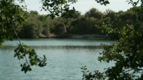 A large body of water which is surrounded by trees in the background