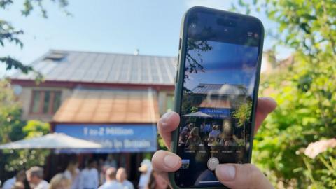 A person holds up a mobile phone to take a picture of the UK's first ever house to be build with a solar roof 30 years ago