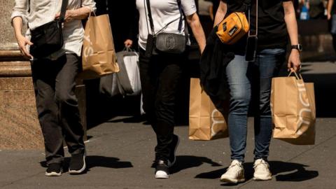 Shoppers carry Macy's bags outside the company's flagship store in New York, US, on Friday, 13 September 2024. 