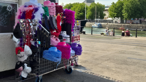 A street vendors stand with colourful hats and trinkets set up by Bristol Harbourside.