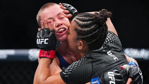 Natalia Silva holds her hands on the face of Rose Namajunas