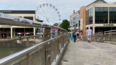 Pero's Bridge with the empty space which the padlocks were attached too. In the background are restaurants, and a large ferris wheel.