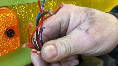 A hand holds wires that have been cut