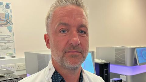 Prof Jim Wilson in his research lab, wearing a white coat