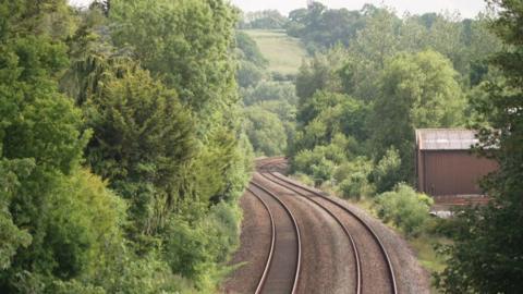 A pair of train tracks wind their way through a wooded area.