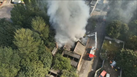 Drone shot showing smoke flowing out of a building.