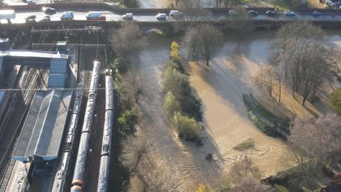 The flooded area around Northampton station following Storm Bert. The river has burst its banks. There are three trains in the station