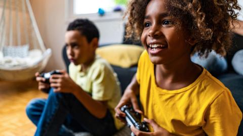 Two kids enjoy playing video games together, holding games controllers